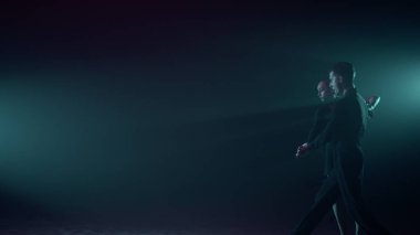 Karanlık sahnede dans eden balo çifti. Dansçılar içeride Latince dans ediyorlar..