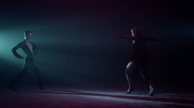 Güzel dansçılar sahnede el kaldırıyor. Kadın ve erkek karanlık salonda dans ediyor..