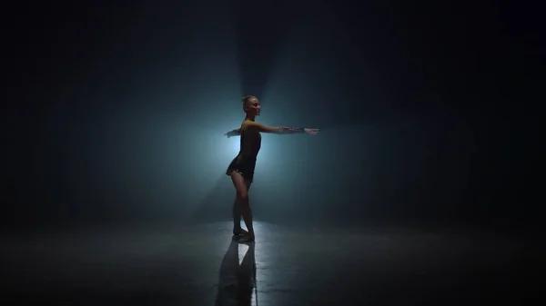 Elegante gimnasta dando vueltas en el interior. Mujer delgada bailando en el espacio oscuro. — Foto de Stock