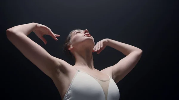 Danseuse tendre regardant vers le haut à l'intérieur. Belle ballerine dansant dans la classe sombre. — Photo