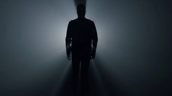 Silhouette ember sétál a sötétben. Férfi személy megy egyenesen a sötétben. — Stock Fotó