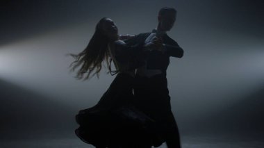 Balo çifti sahnede valiz gösterisi yapıyor. Karanlık salonda dans eden güzel bir çift..