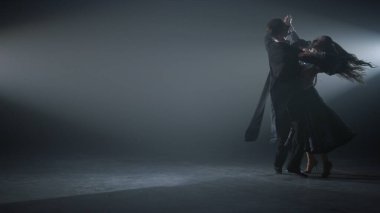 Karanlık sahnede dans eden çift valizi. İçeride vals yapan şehvetli dansçılar..