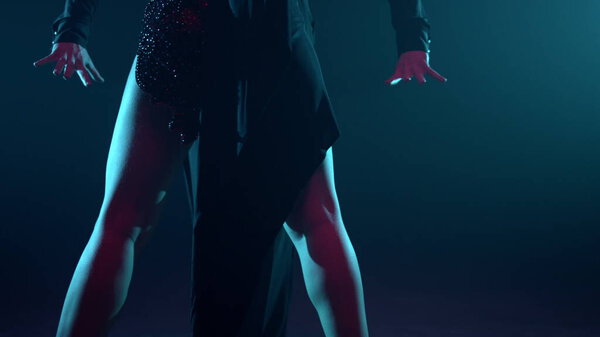 Unknown ballroom dancers performing in dark space. Unrecognizable female dancer bending around male partner indoors. Sexy man and woman dancing inside. Latin dance concept.