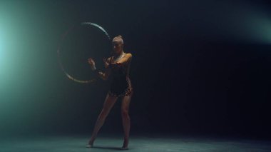 Esnek jimnastikçi hula hoop çeviriyor. Genç bir kadın ritmik jimnastik yapıyor.
