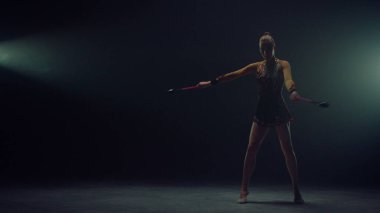 Zarif jimnastikçi içeride ekipmanla egzersiz yapıyor. Kadın biber gazıyla şarkı söylüyor 