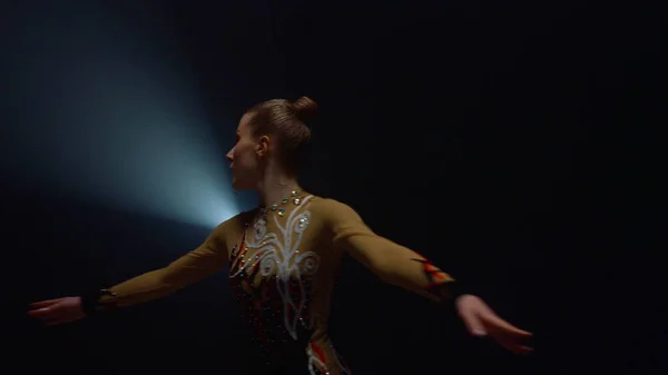 Pretty sportswoman doing rhythmic gymnastics indoors. Beautiful gymnast dancing.