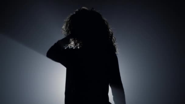 Silueta chica sexy bailando en la oscuridad. Hermosa mujer tocando el pelo. — Vídeos de Stock
