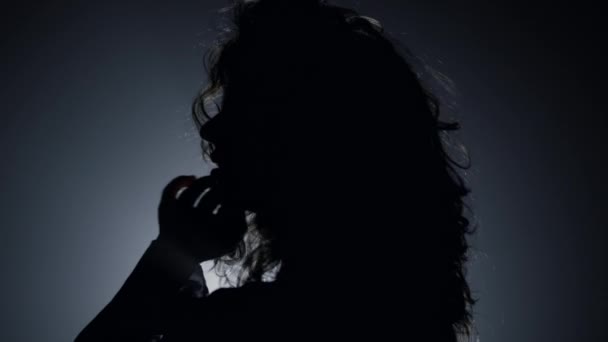 Σιλουέτα όμορφη γυναίκα ποζάρουν κάμερα στο σκοτάδι. Παθιασμένη γυναίκα αγγίζει τα μαλλιά — Αρχείο Βίντεο