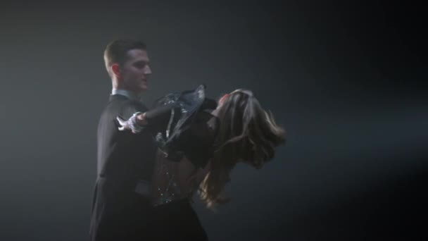 Ballroom danspaar dat ronddraait in de donkere ruimte. Elegante man en vrouw dansen. — Stockvideo