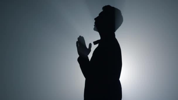 Silhouette religiöser Mann flüstert Gebet drinnen. Gläubige beten im Dunkeln. — Stockvideo