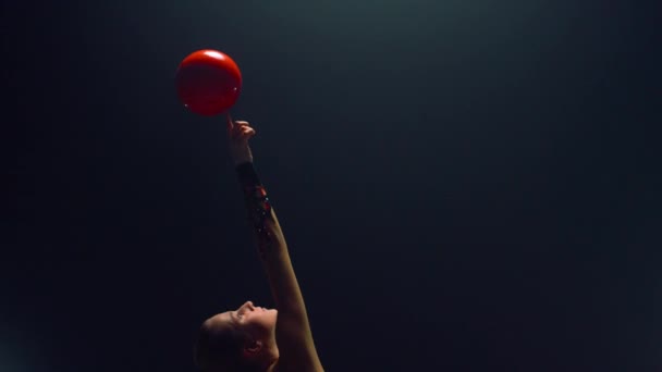 Preciosa mujer haciendo girar la pelota en el dedo levantado. Gimnasta rítmica haciendo ejercicio. — Vídeos de Stock