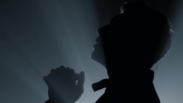 Silhouette religiöser Mann bittet Gott um Segen. Männliche Person betet in der Dunkelheit. — Stockvideo