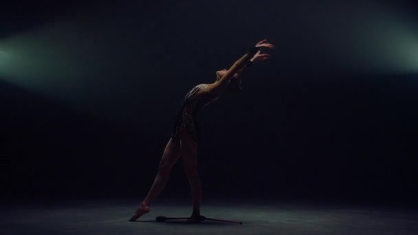 Menina magro jogando macarrão no espaço escuro. Mulher desportiva fazendo salto mortal dentro de casa. — Vídeo de Stock
