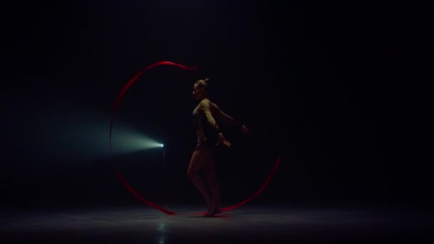 Mujer flexible girando la mano con cinta. Deportiva bailando en el espacio oscuro. — Vídeos de Stock