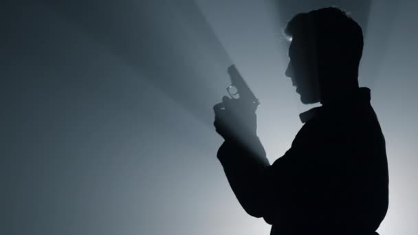 Silhouette male shooter aiming pistol in darkness. Criminal man raising hand gun — Stock Video