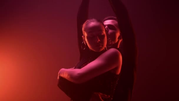 Graciösa par dansar i mörk studio. Flexibla dansare omfamnar inomhus. — Stockvideo