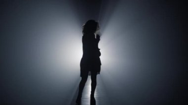 Karanlıkta dans eden siluet kız. Kaygısız kadın karanlık uzayda eğleniyor..