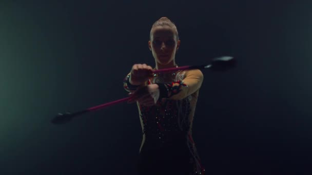 Atletische vrouw die gymnastiek binnen gebruikt. Gymnast spinning clubs binnen. — Stockvideo