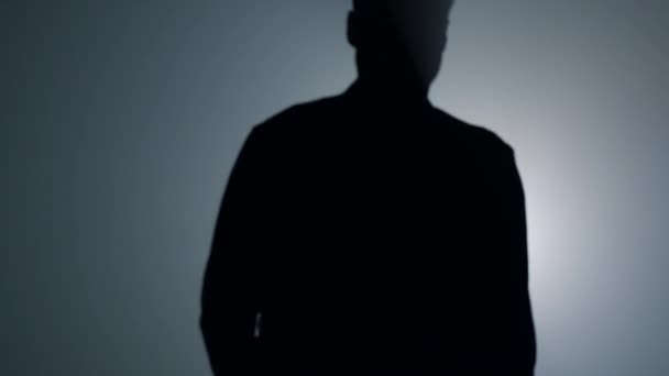 Silhouet man gaat weg op een donkere achtergrond. Terug uitzicht man wandelen in de duisternis. — Stockvideo