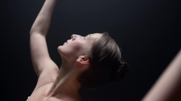 Чувственная балерина танцует в помещении. Артистка балета поднимает руки в темном классе. — стоковое видео