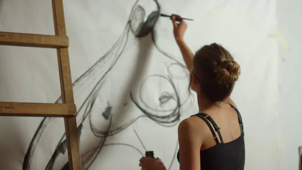 Inspirerad kvinna som ritar i studio. Talangfull målare med svart färg inomhus. — Stockfoto