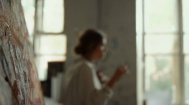 Yetenekli ressam sabahını stüdyoda geçiriyor. Bulanık arka planda yürüyen kız.