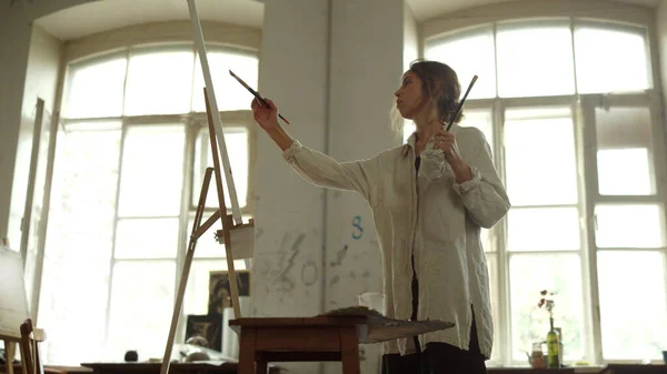 Geïnspireerde vrouw die binnen foto 's maakt. Creatieve schilder verblijft in kunststudio. — Stockfoto