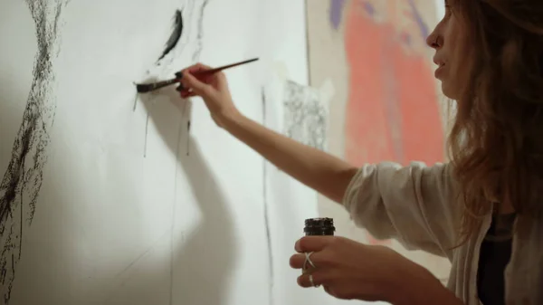 Kvinnlig målare målning med son inomhus. Kvinna skapa konstverk på väggen. — Stockfoto