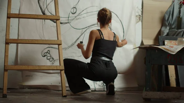 Kvinnlig konstnär hukar sig i studion. Kreativ målare skapa konstverk inomhus. — Stockfoto