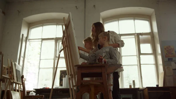 Samtida familjemålning på staffli. Kreativa barn som ritar inomhus. — Stockfoto