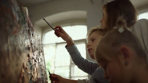 Inspired family drawing together in studio. Female teacher making brush strokes. — Stock Photo, Image