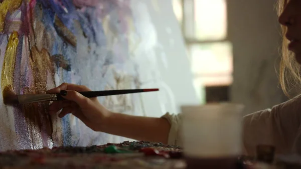 Жінка-художник тримає пензлик в студії. Жінка створює картинку в приміщенні . — стокове фото