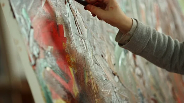 認識できない画家の手は、アートスタジオでキャンバス上のブラシストロークを作る. — ストック写真