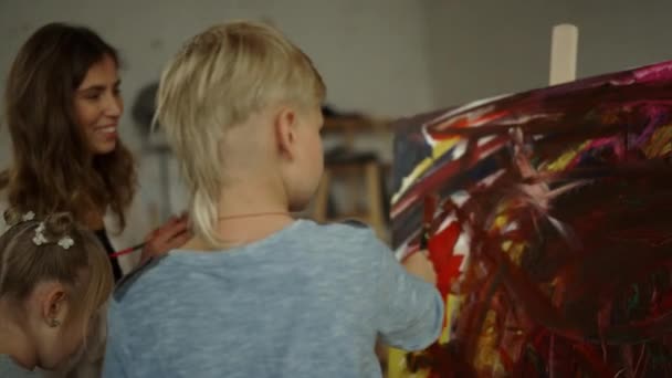 Inspirierte Familie, die Kunstwerke in Innenräumen schafft. Junge Malerin unterrichtet Kinder. — Stockvideo