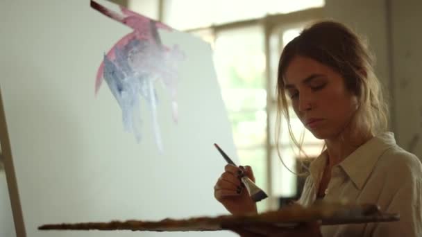 Wanita kreatif menerapkan cat di atas kanvas. Lukisan cat di dalam ruangan. — Stok Video