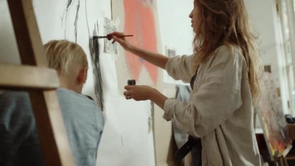 Mujer creativa dibujando sobre lienzo. Pintora hablando en un estudio de arte. — Vídeo de stock