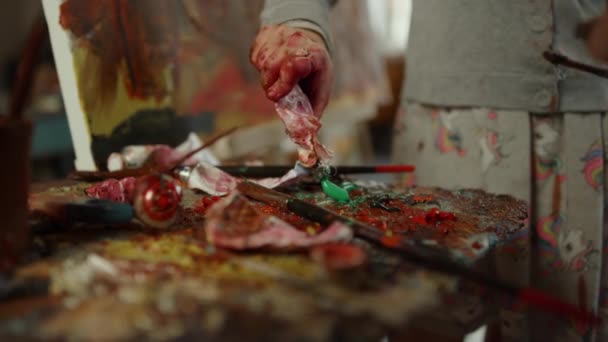 Personas desconocidas pasan tiempo en el taller. Pintor mano mezcla pintura en la paleta. — Vídeos de Stock