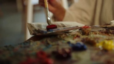 İş yerinde boyaları karıştıran yaratıcı bir kadın. Kapalı alanda fırça kullanan tanınmamış bir ressam.