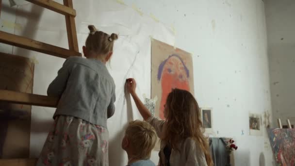 Visão traseira do pintor feminino e crianças pintando na parede com giz preto. — Vídeo de Stock