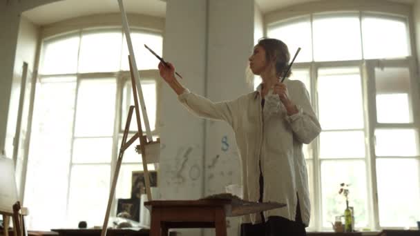 Вдохновлённая женщина создаёт картину в помещении. Живописец остается в художественной студии. — стоковое видео