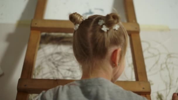 白い壁に小さな画家の絵。屋内で作品を作る才能のある少女. — ストック動画