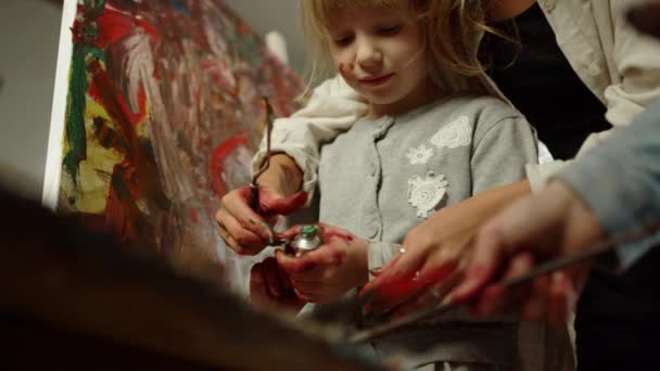 無名の女性がアートスタジオで時間を過ごす。屋内で絵具を絞るフォーカスガール. — ストック動画
