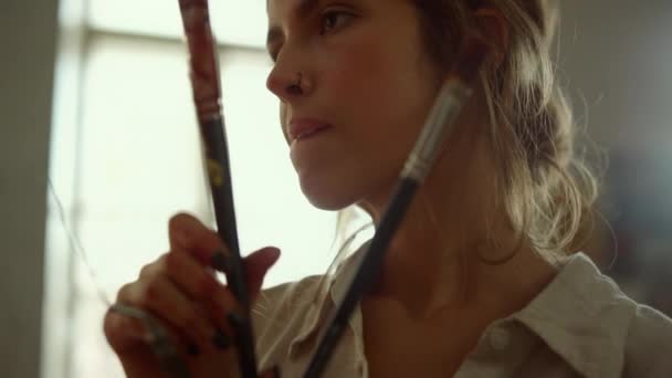 Inspirado pintor olhando no estúdio de arte. Focado menina segurando ferramentas dentro de casa. — Vídeo de Stock