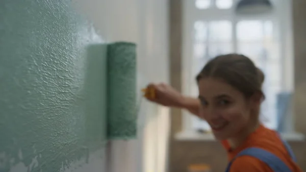 Mujer feliz haciendo reparaciones en casa en interiores. Chica haciendo tira ancha de pintura en la pared. — Foto de Stock