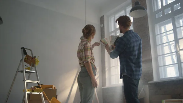 Familia joven alojada entre herramientas de construcción. Pareja elegir paredes color. — Foto de Stock