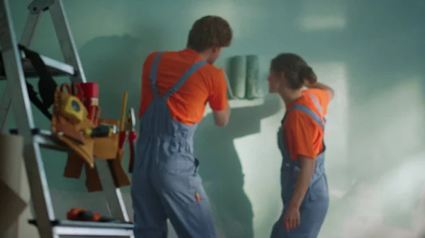 Cheerful woman diving under man hand indoors. Couple during home renovation. — Stock Photo, Image