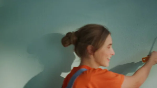 Hombre y mujer sonrientes pintando la pared con rodillo de pintura en nuevo apartamento. — Foto de Stock
