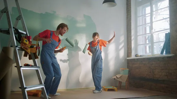 Familia activa cantando con rodillos durante la renovación de la casa en un apartamento nuevo. — Foto de Stock