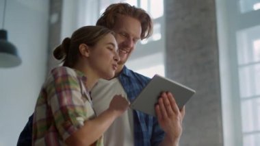 Neşeli çift, ev dekorasyonunun keyfini çıkarıyor. Kapalı alanda tablet kullanıyorlar..
